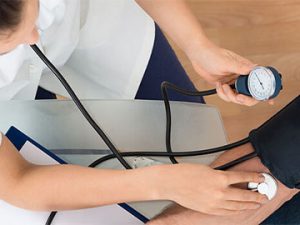 medical professional uses blood pressure cuff on patient
