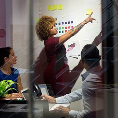 woman leading team meeting and pointing to white board
