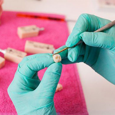 hands fixing tooth in lab