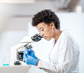 woman examines sample near microscope