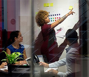 woman leading team meeting and pointing to white board
