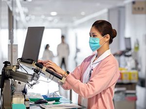 woman typing medical information into laptop