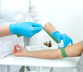 phlebotomist tying off patient arm for blood draw