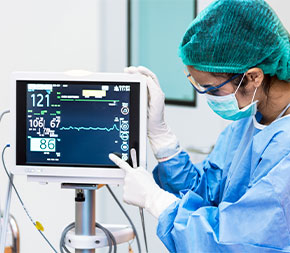 masked tech prepares vital stats machine for surgery