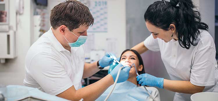 two dental assistants cleaning patient's teeth