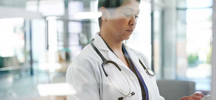 woman in scrubs looking at tablet