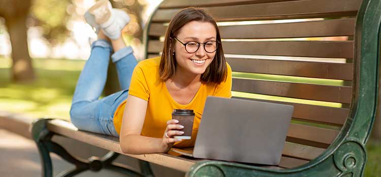 woman on park bench researching jobs on laptop