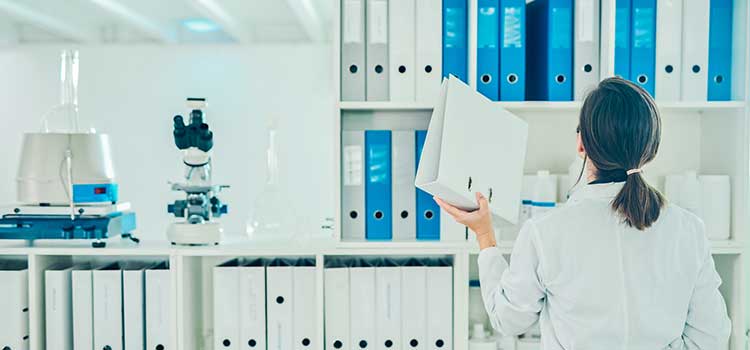 woman with back to camera filing binder in library