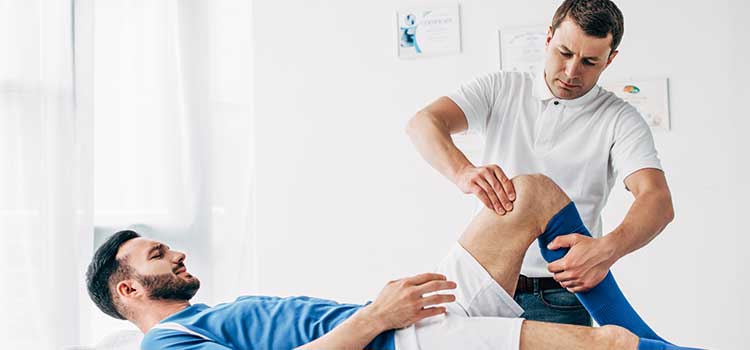 sports massage therapist massaging soccer player's knee