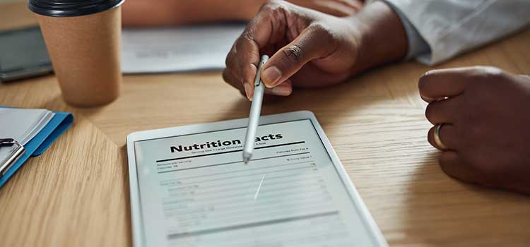 hand with pen pointing to nutrition information on table