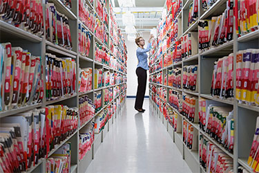 person returns file to top shelf of file library row