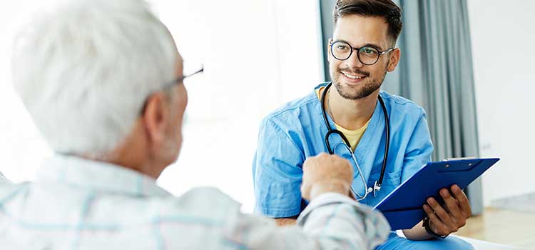 make CNA holding clipboard and talking with older male patient