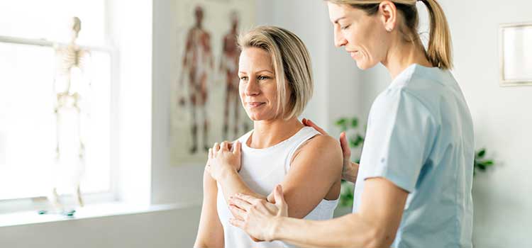 female nurse assistant helps patient with shoulder pain