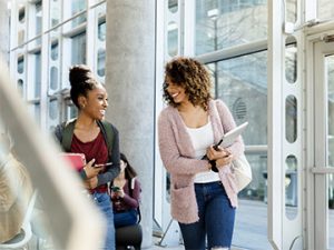 two students chatting in windowed hallway
