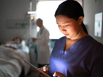 medical professional looks at tablet in patient room