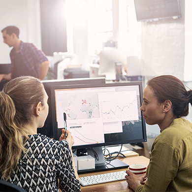 two office professionals discussing screen with charts