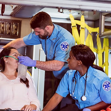 emergency medical technicians helping patient with oxygen mask