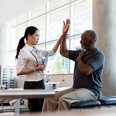 medical professional helps patient move arm above head