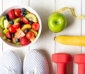 bowl of cut fruit next to running shoes and fruit