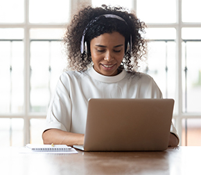 person working on laptop at desk with notepad