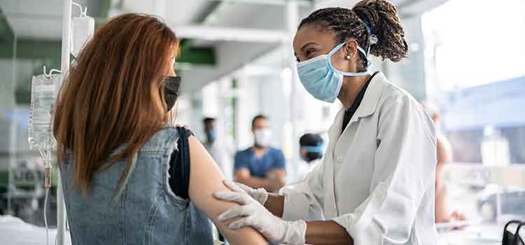 epidemiologist administering vaccine to female patient