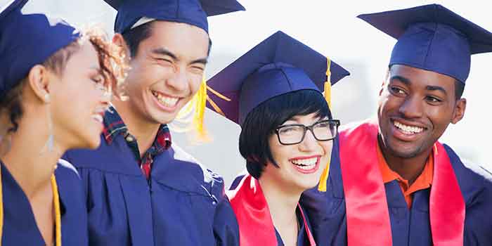 four graduates in caps and gowns