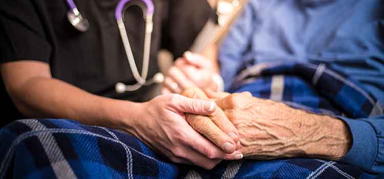 close up of health care provider holding older person's hand