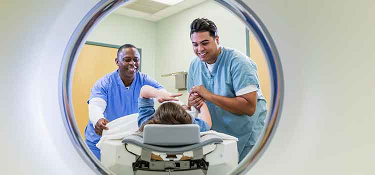 two radiology techs helping patient in MRI machine