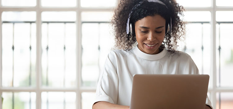 female student with headphones doing work on laptop