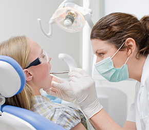 dental assistant cleaning patient teeth