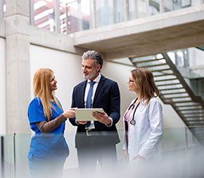 a healthcare manager speaks with two healthcare providers in a medical facility