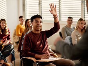 a healthcare administration student raises his hand to ask a question during class