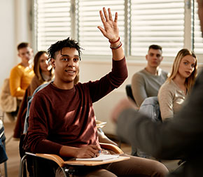 a healthcare administration student raises his hand to ask a question during class