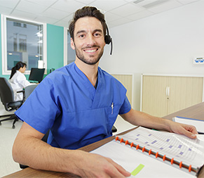 smiling medical administrative assistant schedules appointments in busy office