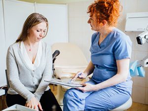 a medical assistant sits down and reviews medical history with a patient