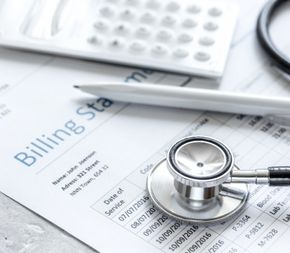 a medical billing statement rests on a table underneath a stethoscope