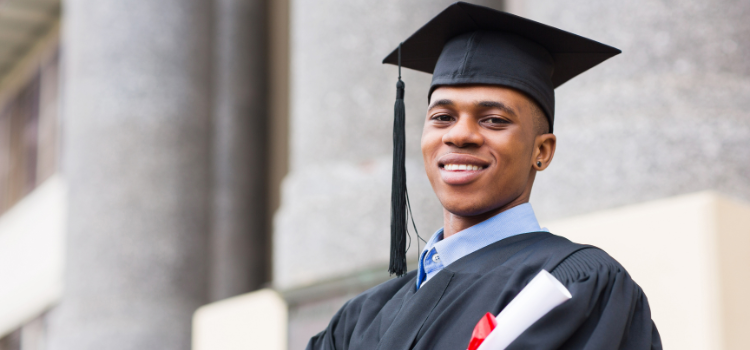 high school grad smiles at the camera and holds his diploma